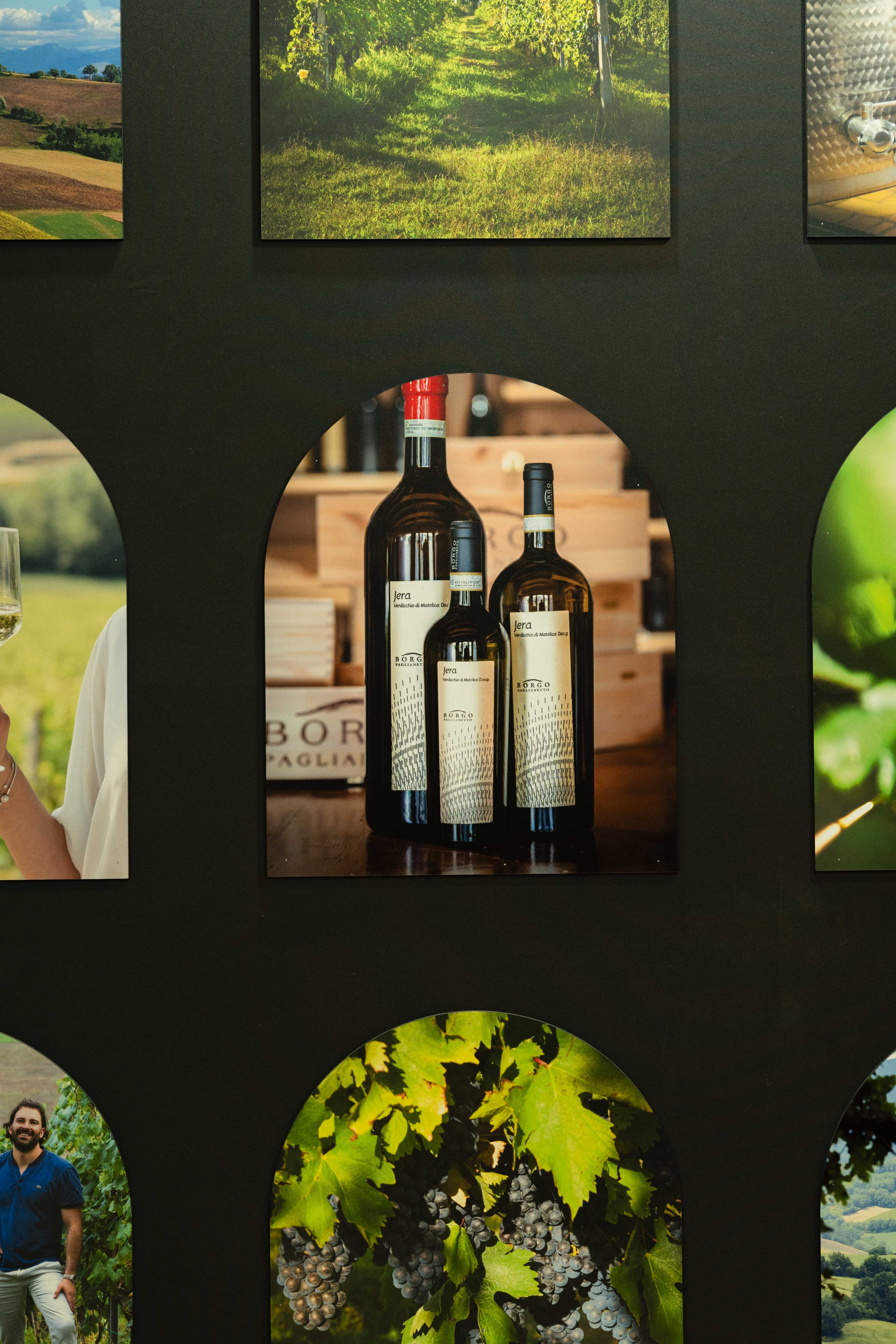 Primo piano dell’esposizione dei vini Jera di Borgo Paglianetto, inserita in una cornice a forma di arco all’interno dello stand.