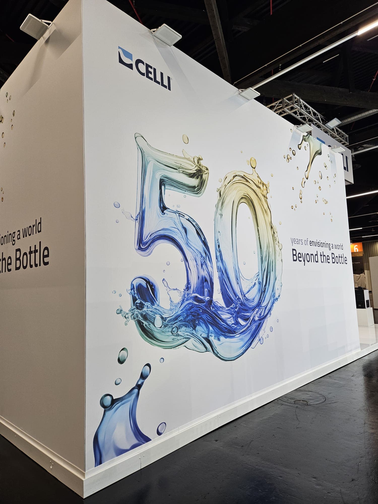 Parete esterna dello stand Celli con visual dinamico per celebrare il 50° anniversario del brand, caratterizzato da elementi liquidi e colori vivaci.
